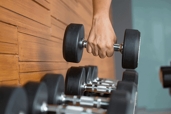 person lifting a dumbbell off of a dumbbell rack