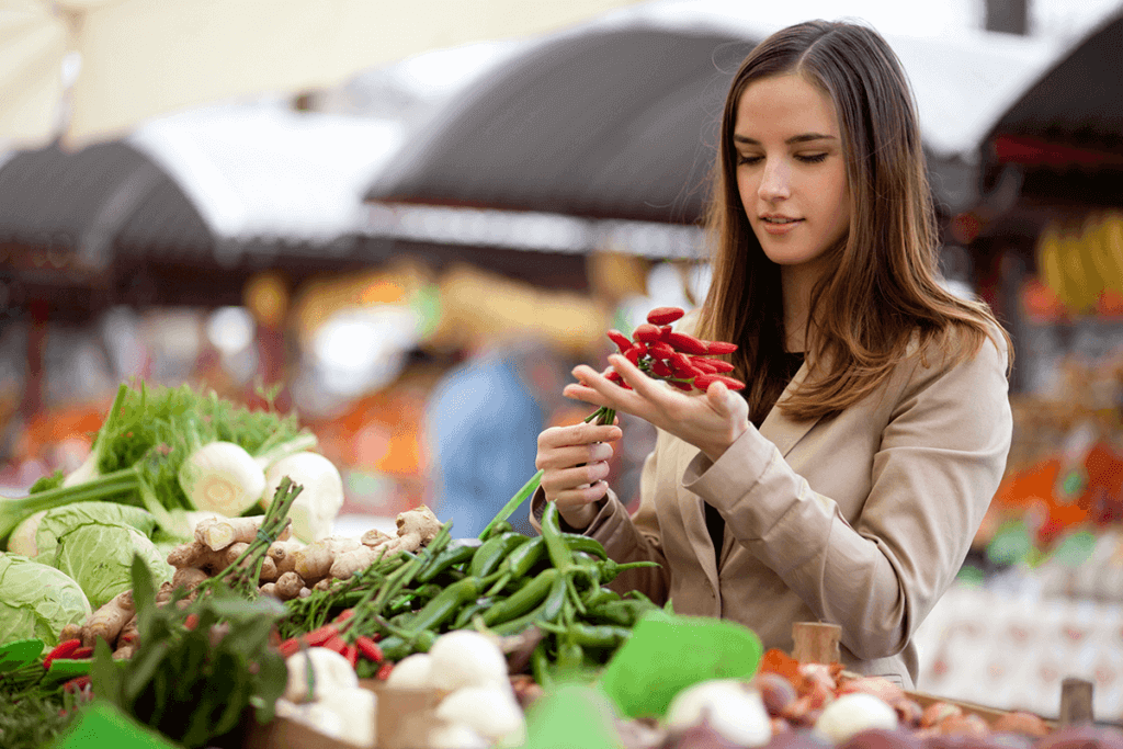 woman holding red chilly peppers in local food market