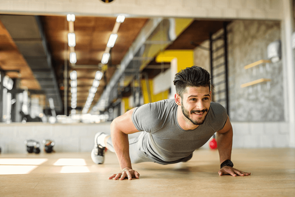 MAN WORKING OUT WITH PUSH UPS AT THE GYM