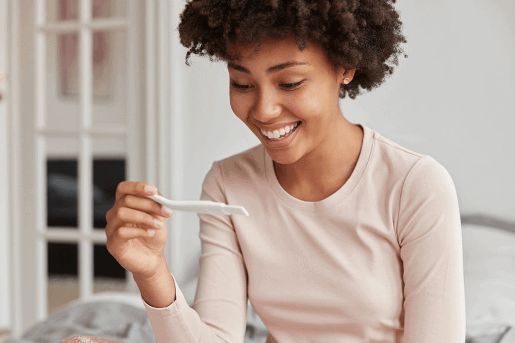 woman holding a pregnancy test and smiling at it