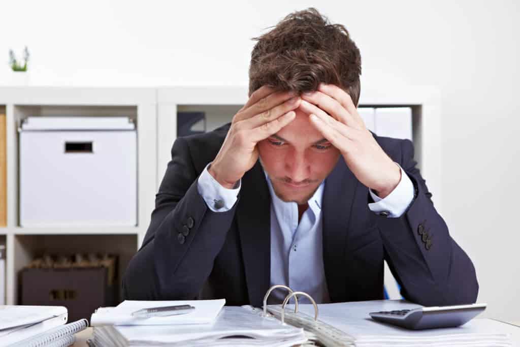 Man sitting at a desk holding his head, stressed