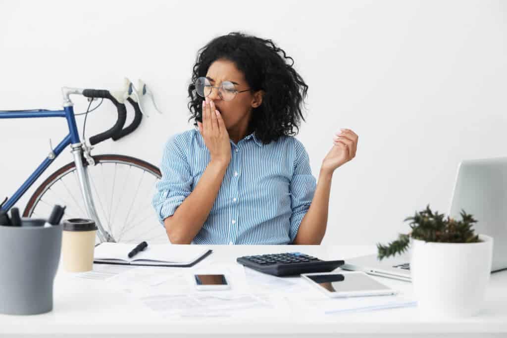 Woman sitting at her desk yawning
