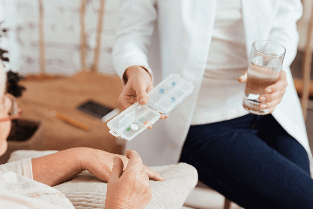 nurse practitioner holding water and a pill box reaching out to patient