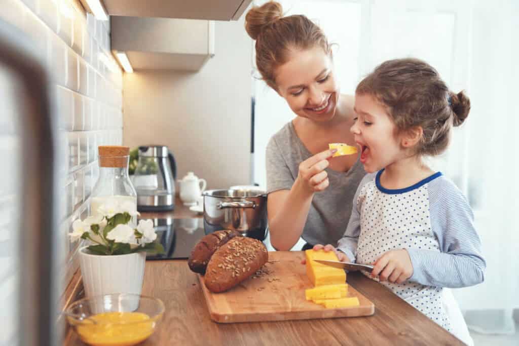 woman feeding her daughter cheese
