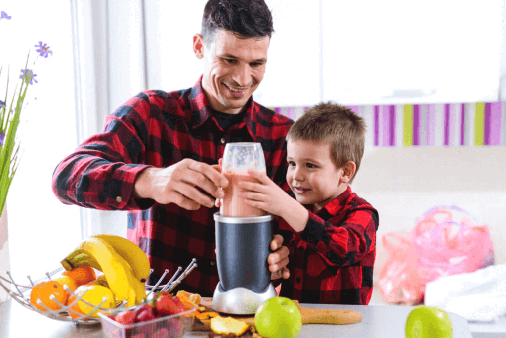father and son making a smoothie in the kitchen