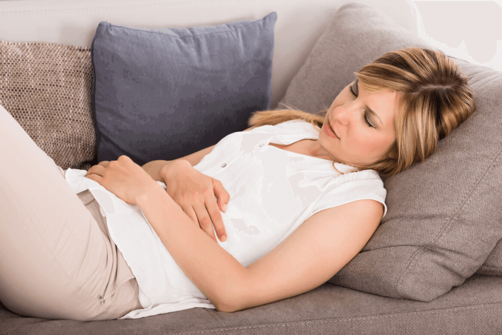 woman holding her stomach laying on couch