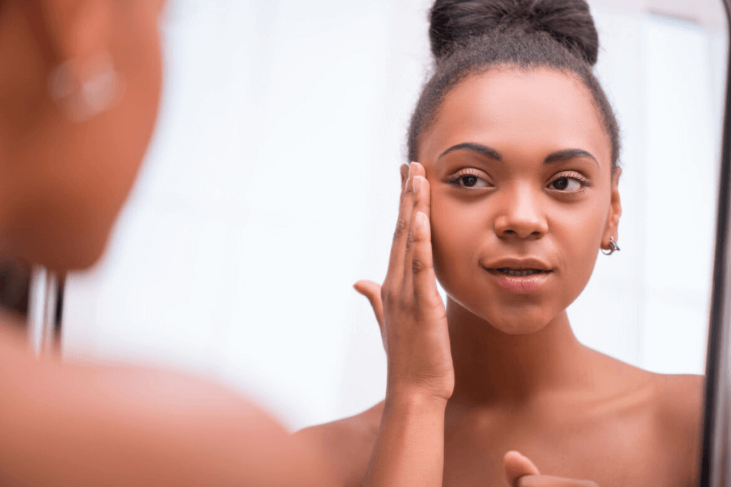 woman looking at her skin in mirror