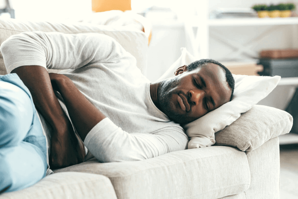 person lying on couch holding their stomach