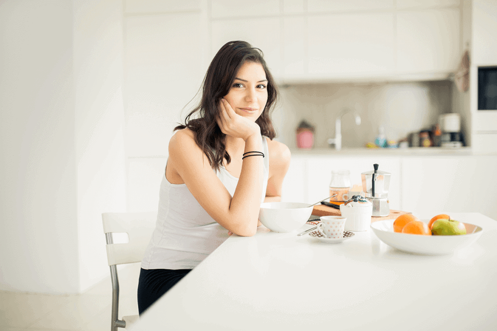 smiling woman with a thoughtful expression, resting her hand on her chin