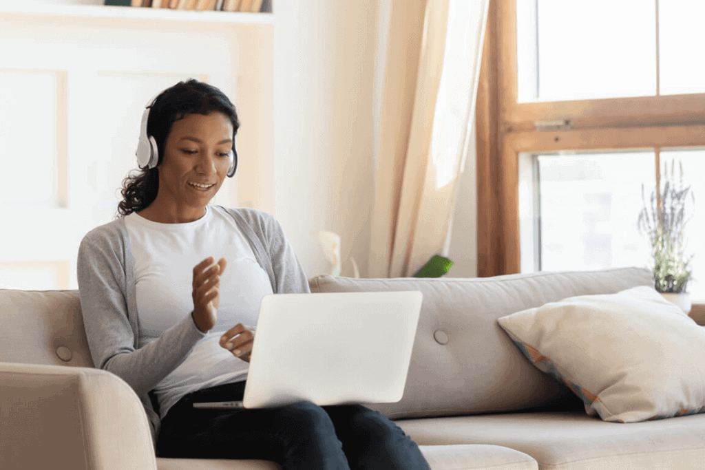 person talking with headphones on laptop in living room