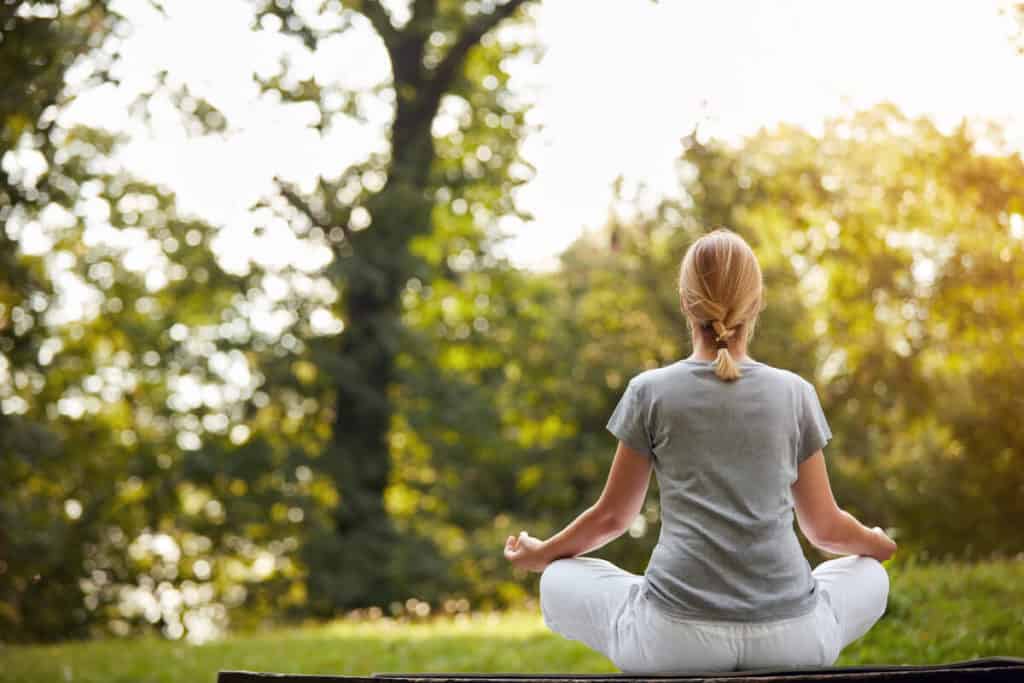 Woman meditating in a grassy area