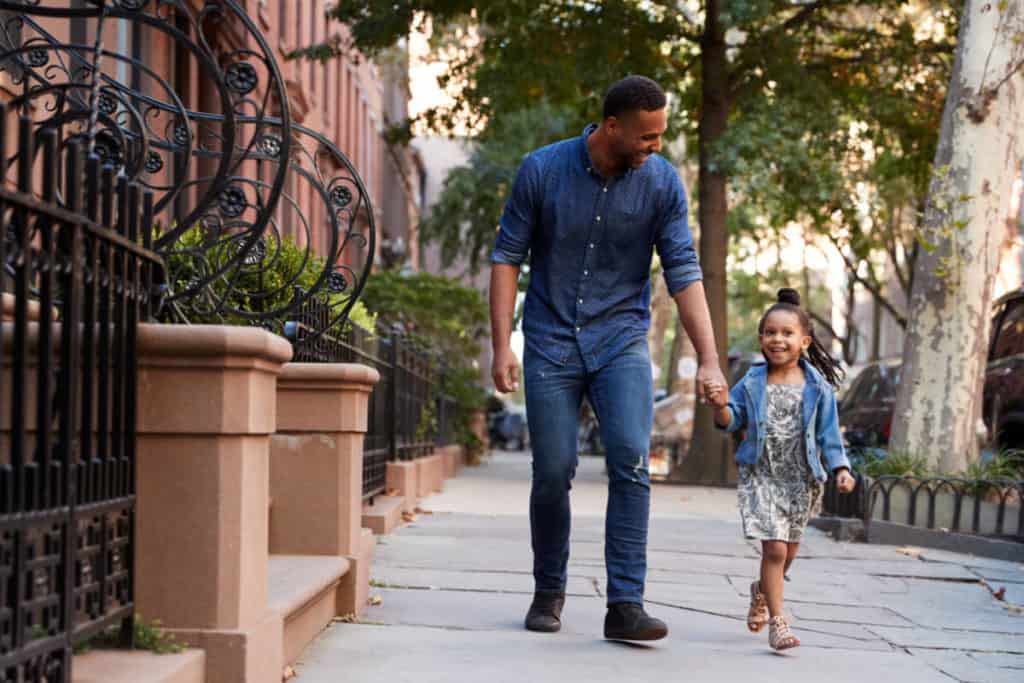 Man holding the hand of a child walking down the street