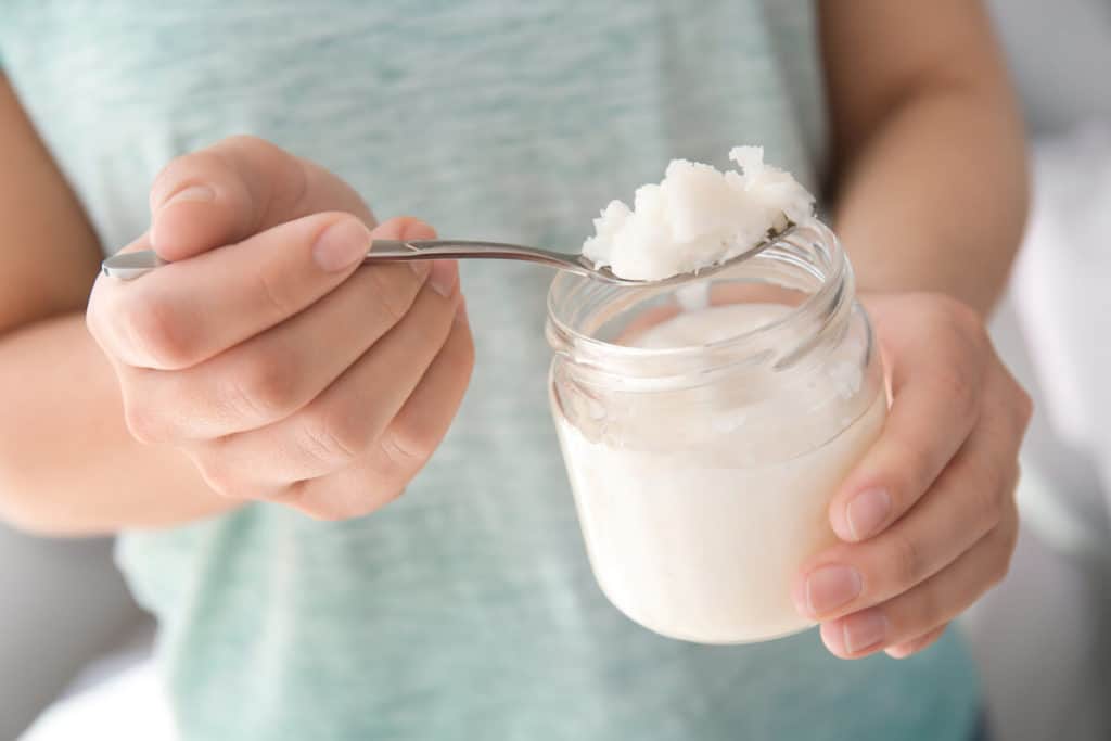 Woman scooping virgin coconut oil out of a jar